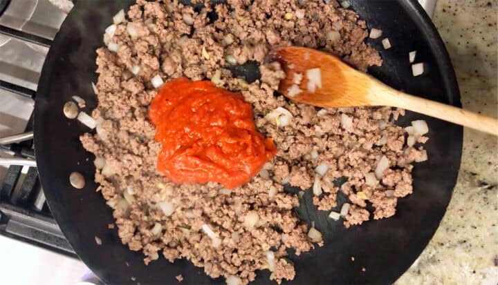 Adding marinara sauce to the skillet.