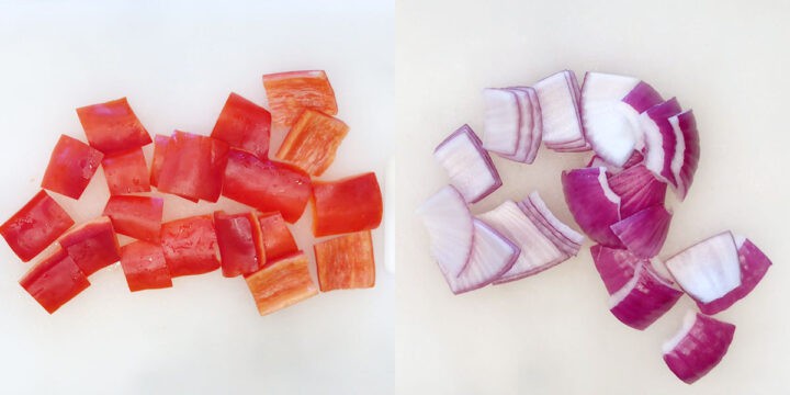 Peppers and onions are chopped on a cutting board.