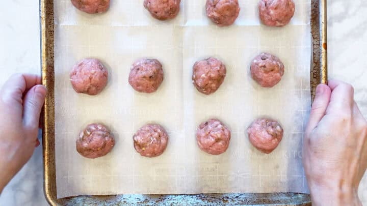 The raw meatballs are arranged in a pan.
