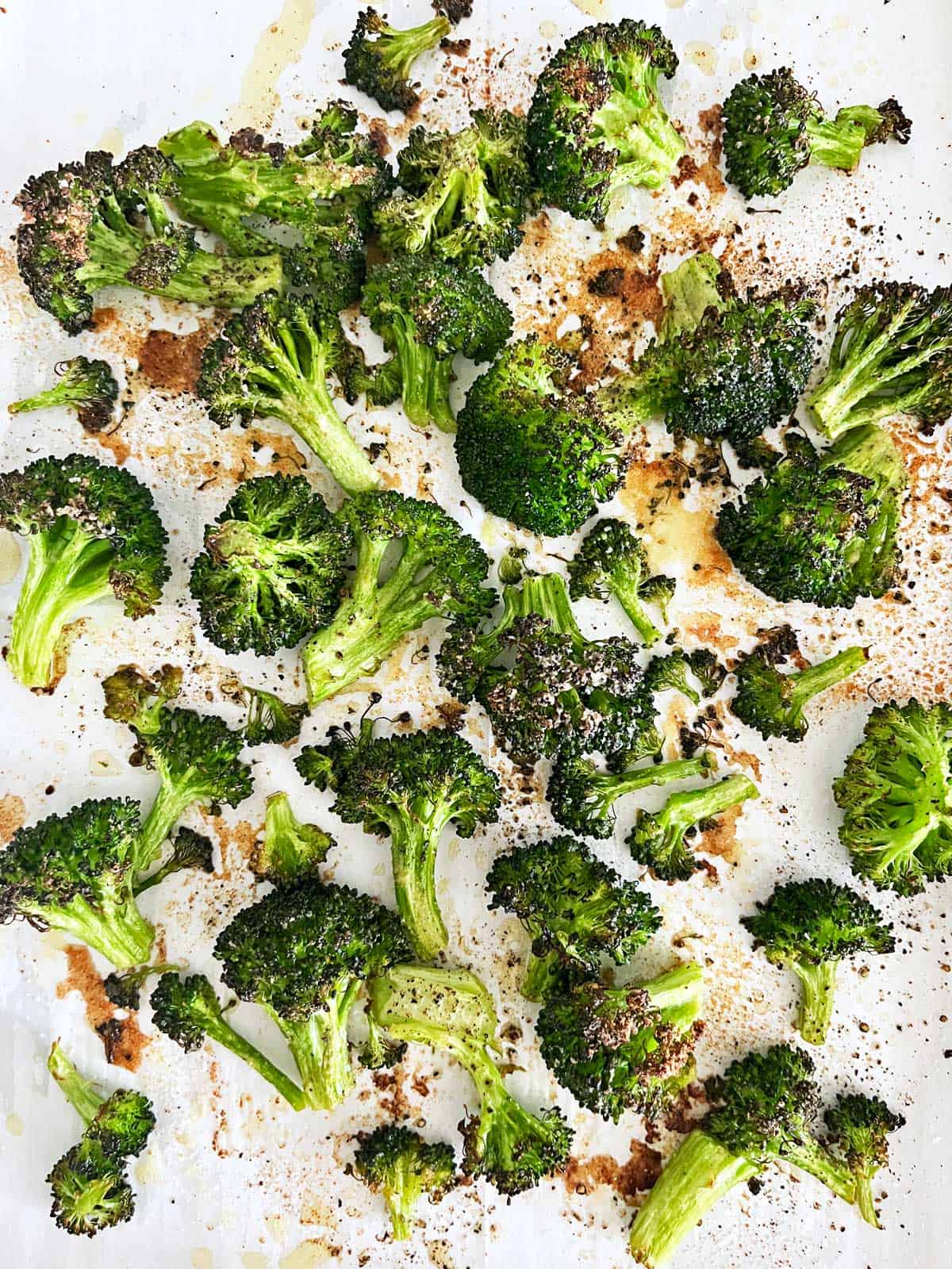 Oven-roasted broccoli on a parchment-lined baking sheet.