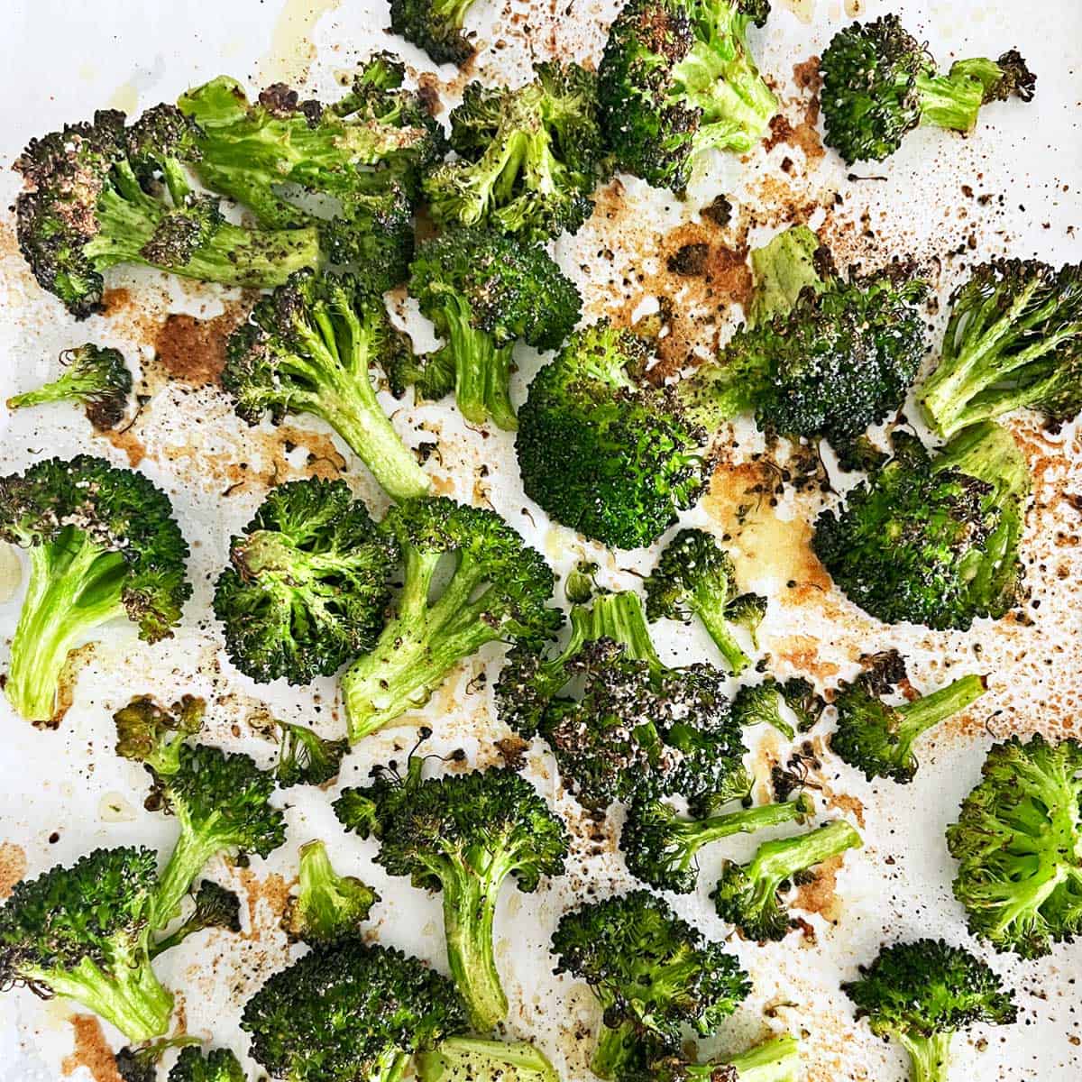 Oven-roasted broccoli on a parchment-lined baking sheet.