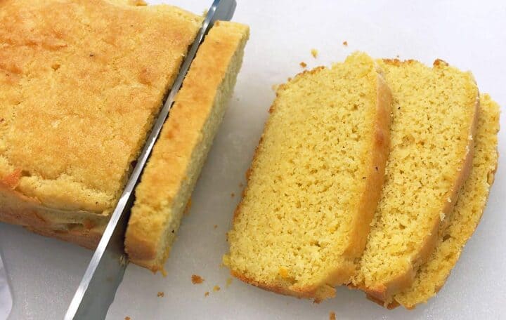 The cake is being sliced with a knife on a cutting board.