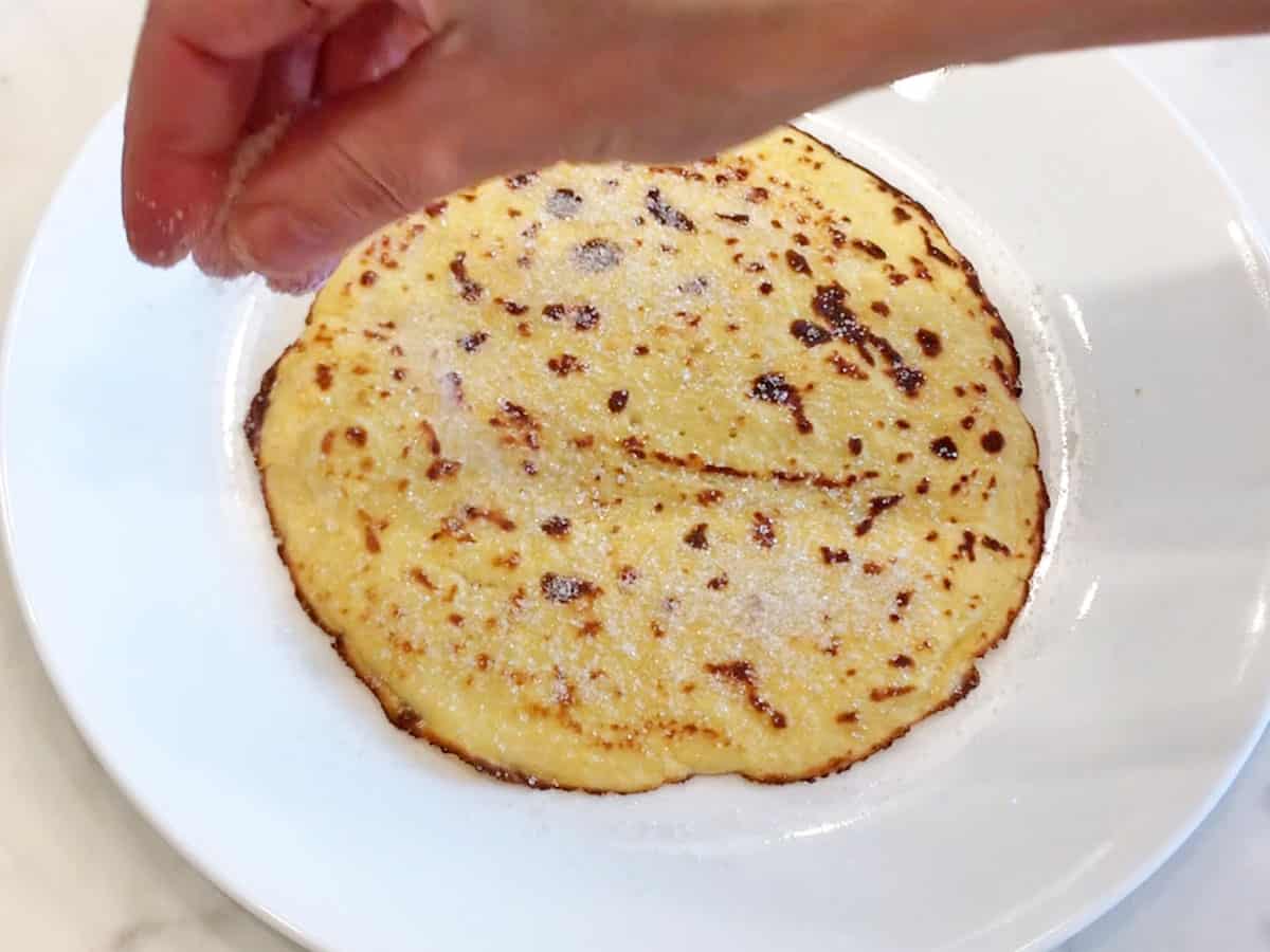 Sprinkling a pannenkoeken with sugar.