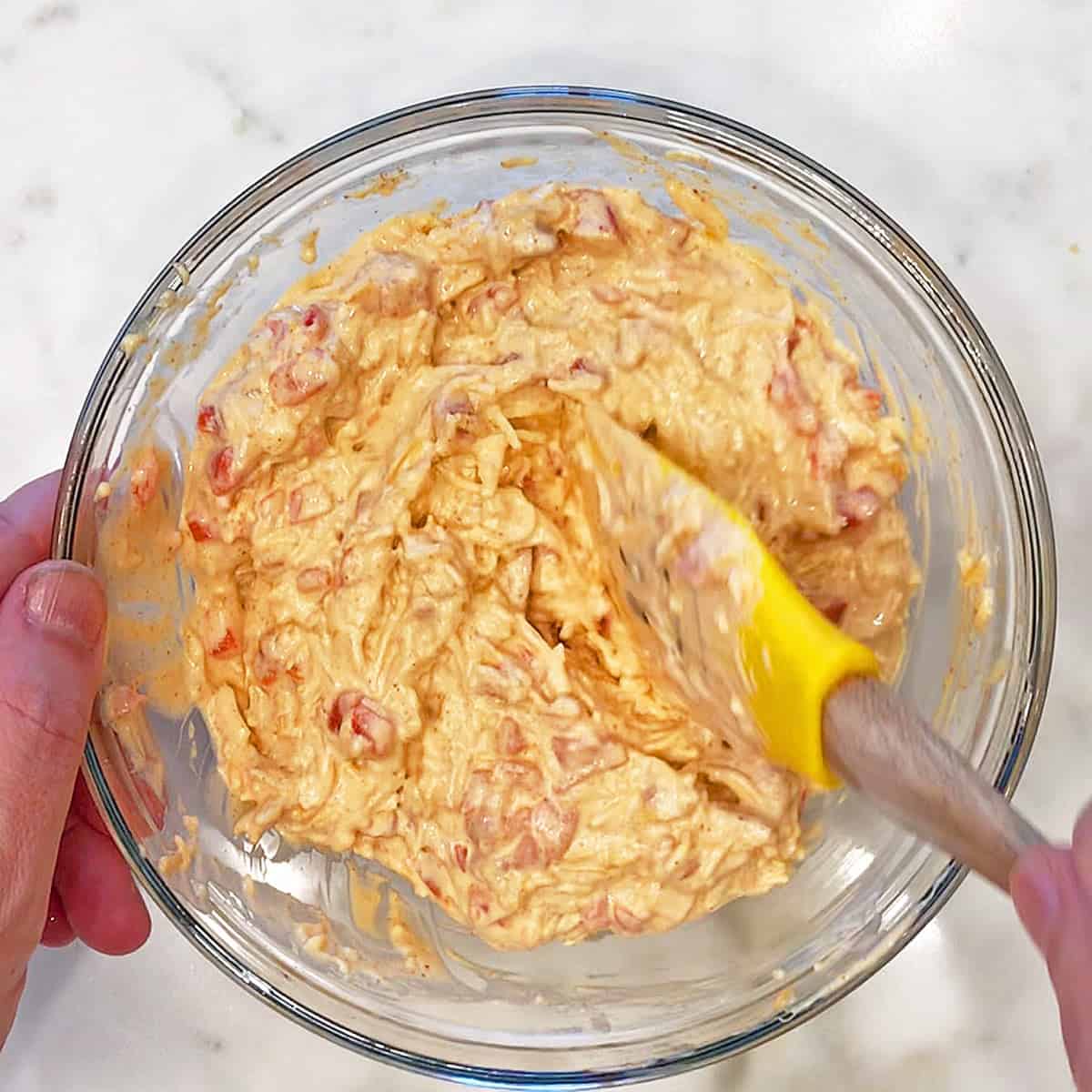 Adding shredded cheddar and pimento peppers.