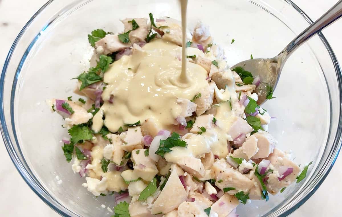 Adding the dressing to the salad.