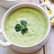 Avocado soup is served in a white bowl.