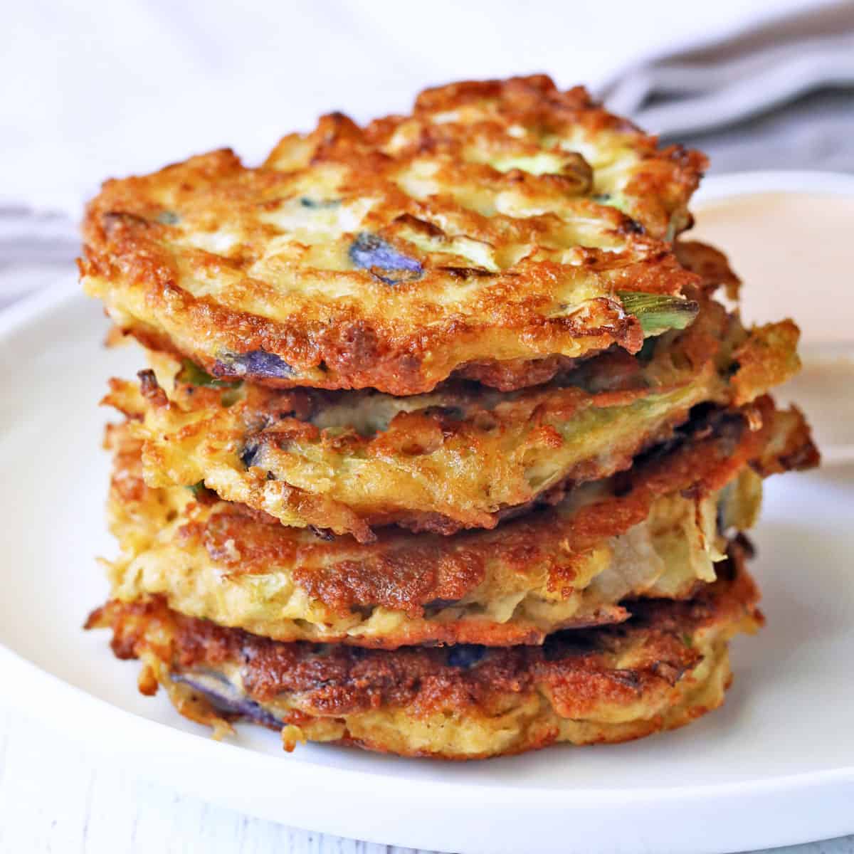 A stack of cabbage pancakes served with a dipping sauce.
