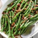 Green beans with bacon are served with a serving spoon.