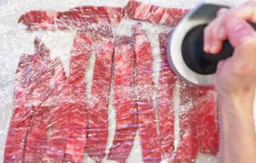 Pounding the beef strips thin.