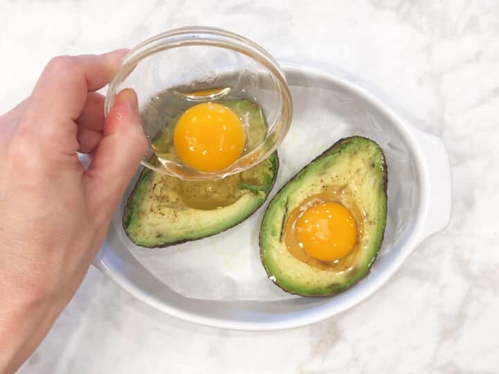 Pouring the eggs into the avocado halves.