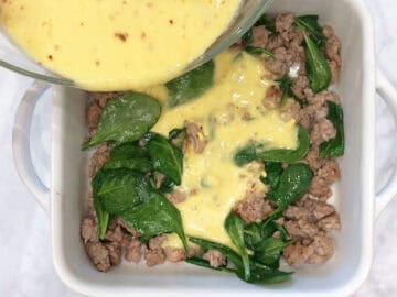 Pouring the egg mixture on top of the sausage and spinach.