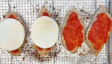 Topping the chicken with marinara sauce and cheese.