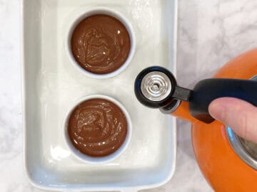 Placing the ramekins in a water bath.