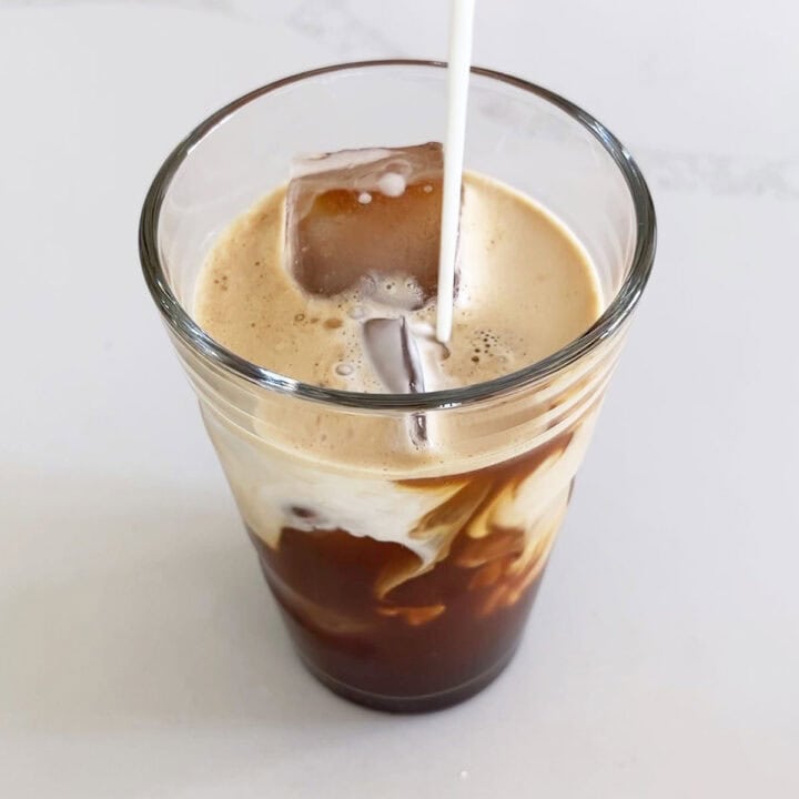 Adding heavy cream to the coffee.