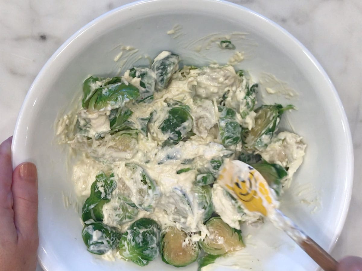 Mixing the sauce into the sprouts.