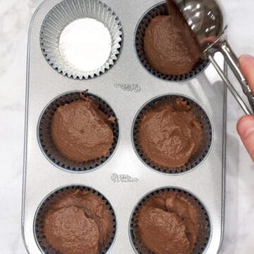 Dividing the batter between the muffin pan cavities.