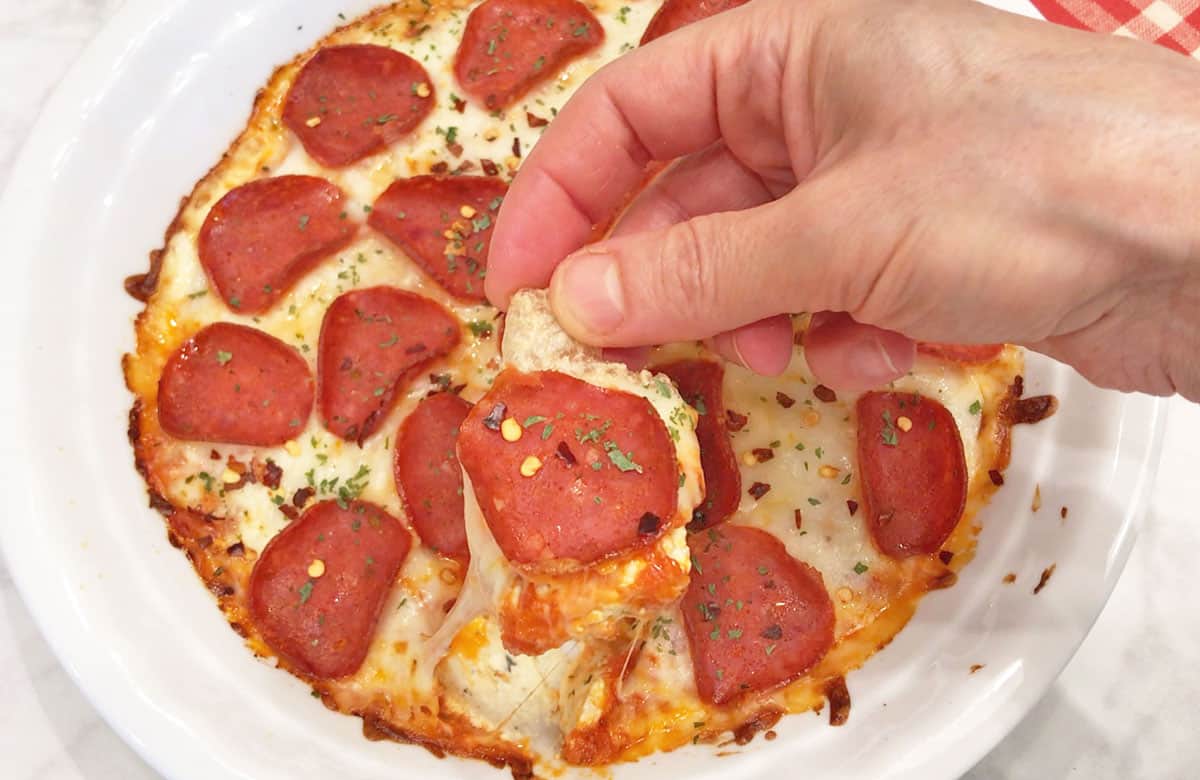 Scooping the dip with pork rinds.