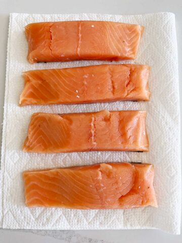 Blotting the salmon dry on paper towels.