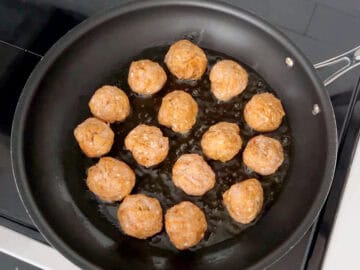 Browning the meatballs in a skillet.