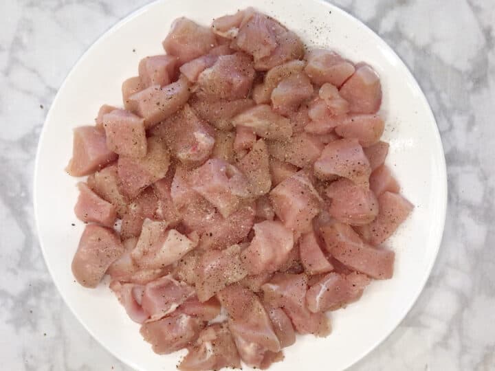 Seasoned chicken cubes on a white plate.