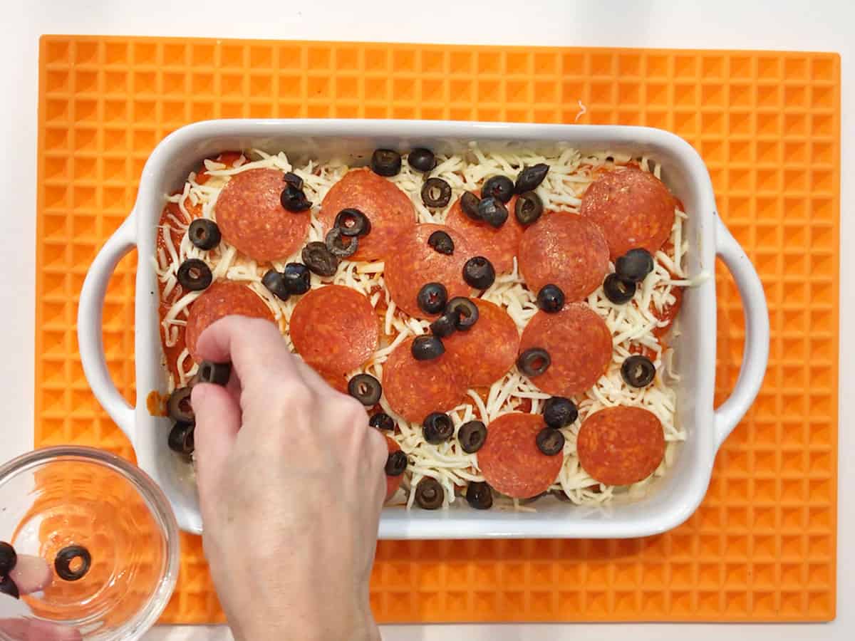 Topping the chicken with olives.