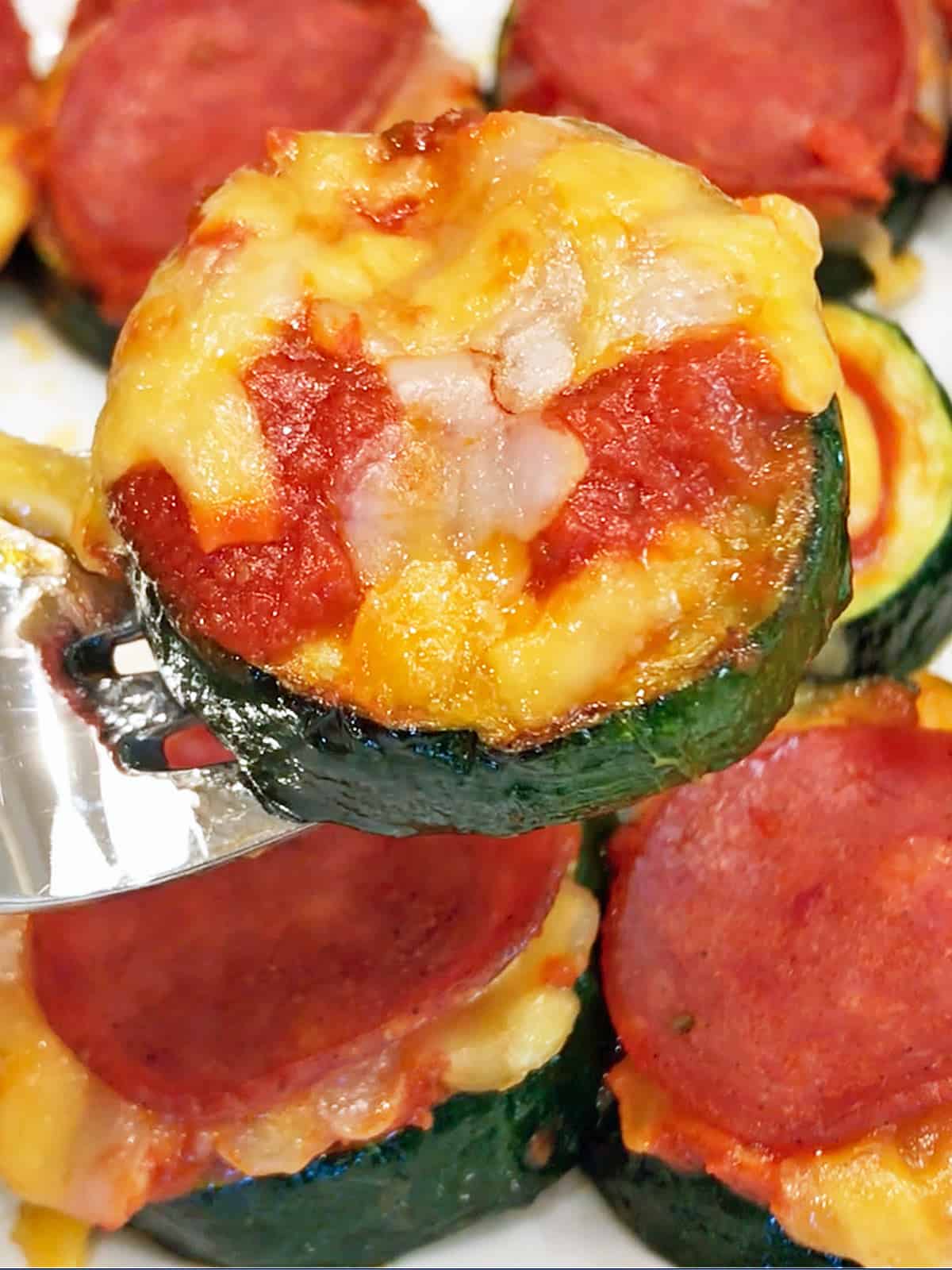 Zucchini pizza bites are served with a fork.