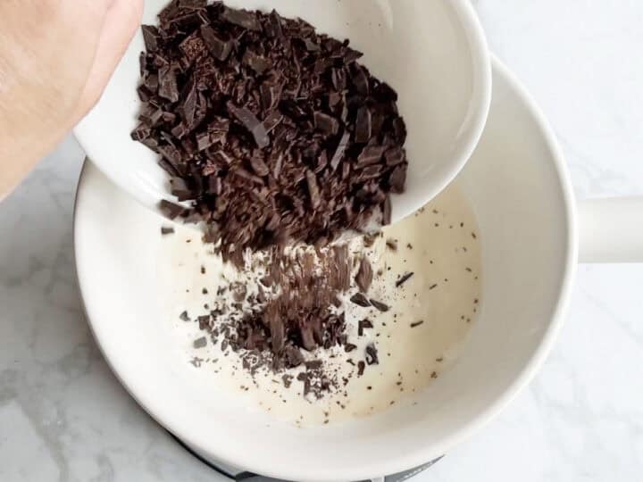 Adding the chopped chocolate to the fondue pot.