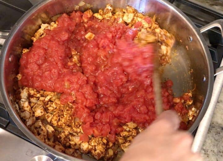 Adding tomatoes to the saucepan.