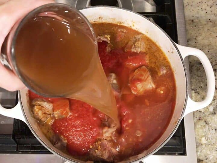 Adding beef broth to the saucepan.