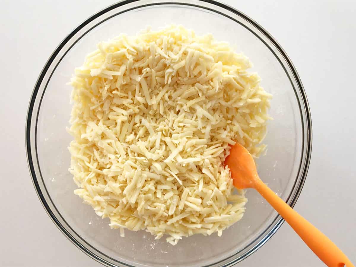 Shredded cheese were mixed with cornstarch and spices in a bowl.