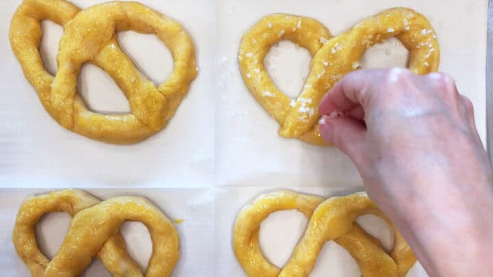 Topping the pretzels with coarse salt.