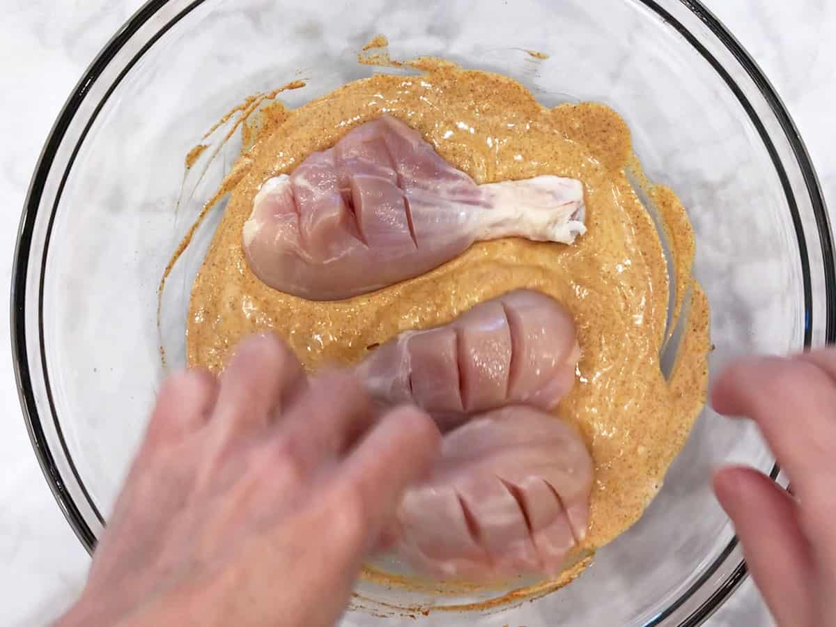 Coating the chicken in the yogurt marinade.