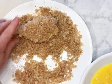 Dredging the chicken in crushed pork rinds.
