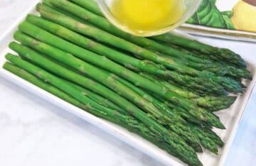 Drizzling the steamed asparagus with melted butter.