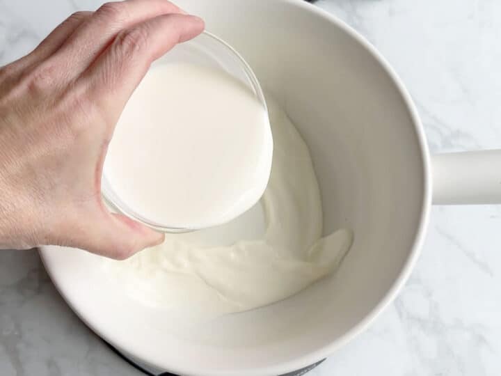 Adding heavy cream to the fondue pot.