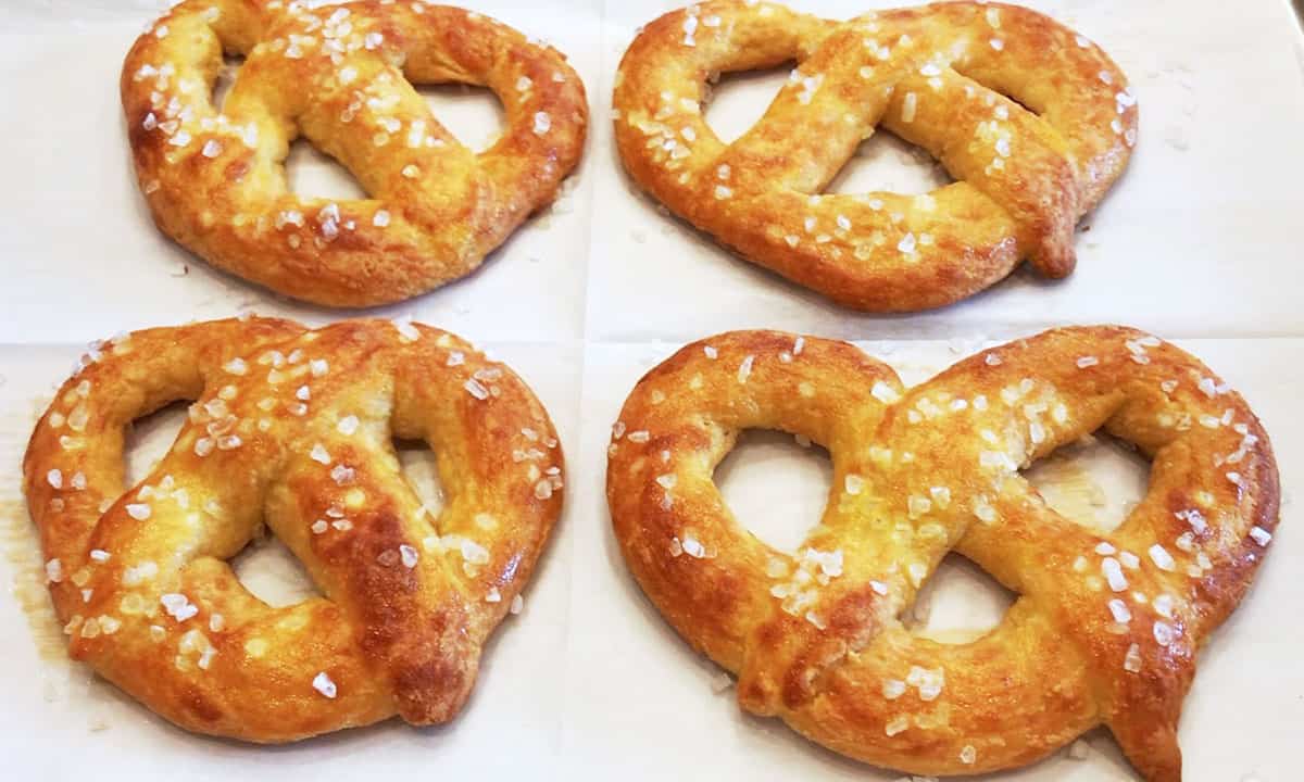 Four keto pretzels are ready on a baking sheet.