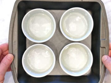 Four greased ramekins in a rimmed baking dish.