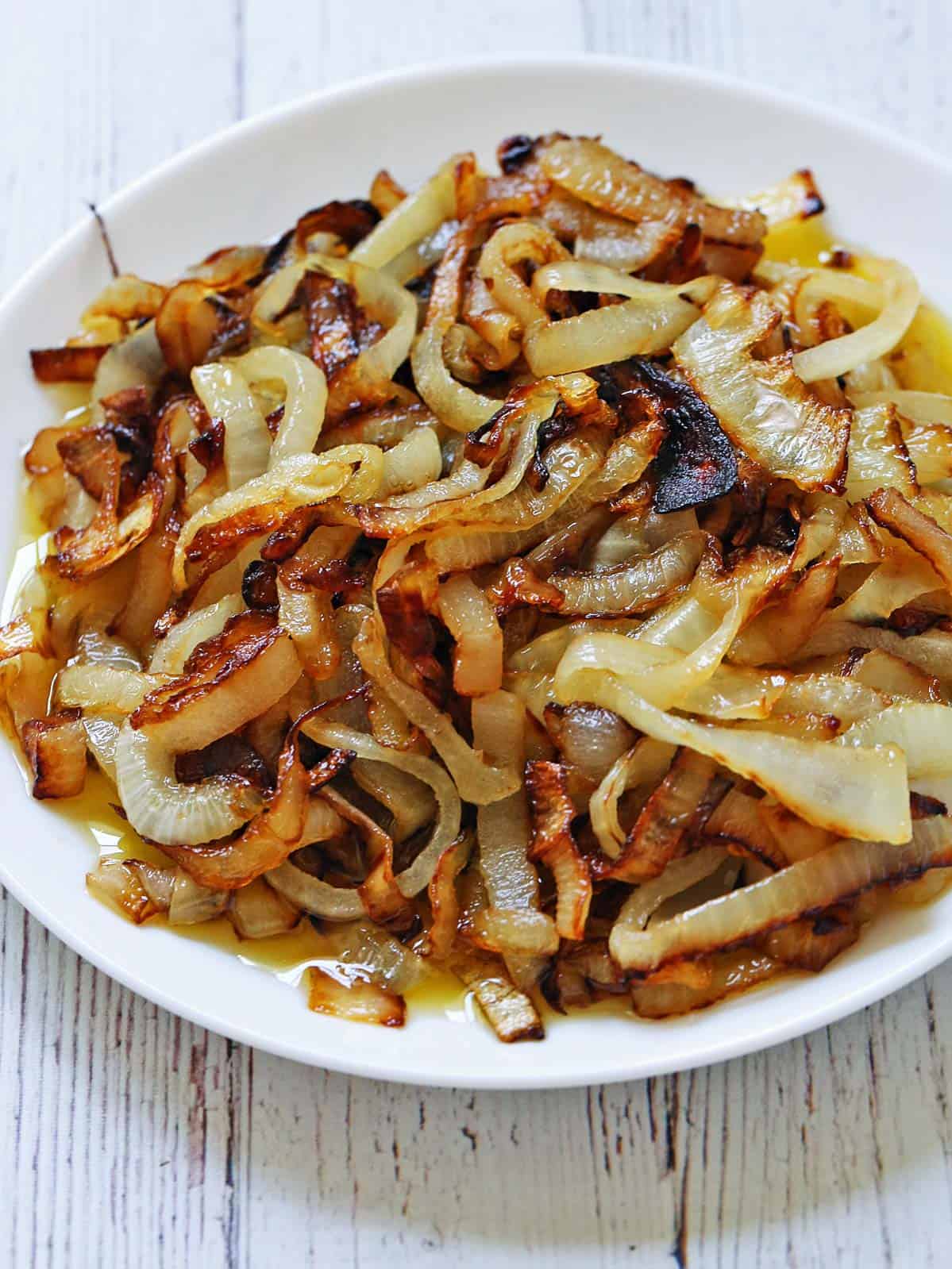 Sauteed onions are served on a white plate.
