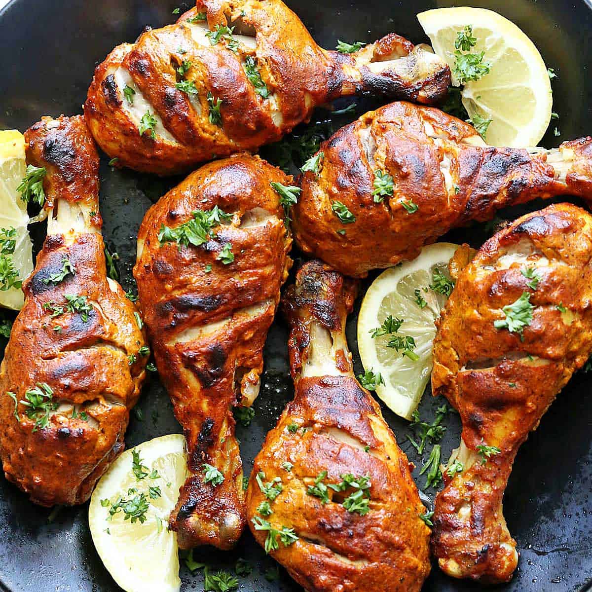 Oven tandoori chicken is served with lemon slices.