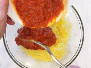Adding marinara sauce to the squash.