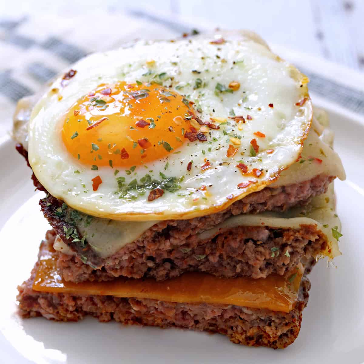 Baked hamburgers are topped with a fried egg.