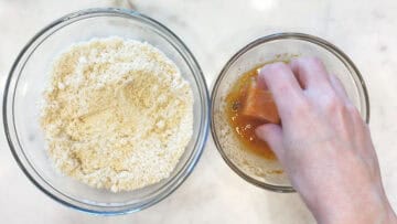 Dipping a piece of chicken in the egg mixture.