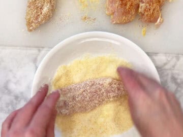 Dipping the chicken tenders in grated parmesan.