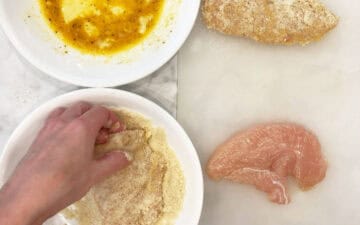 Dredging a chicken tender in almond flour.