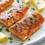 Grilled mahi mahi is served on a white plate with lemon slices.