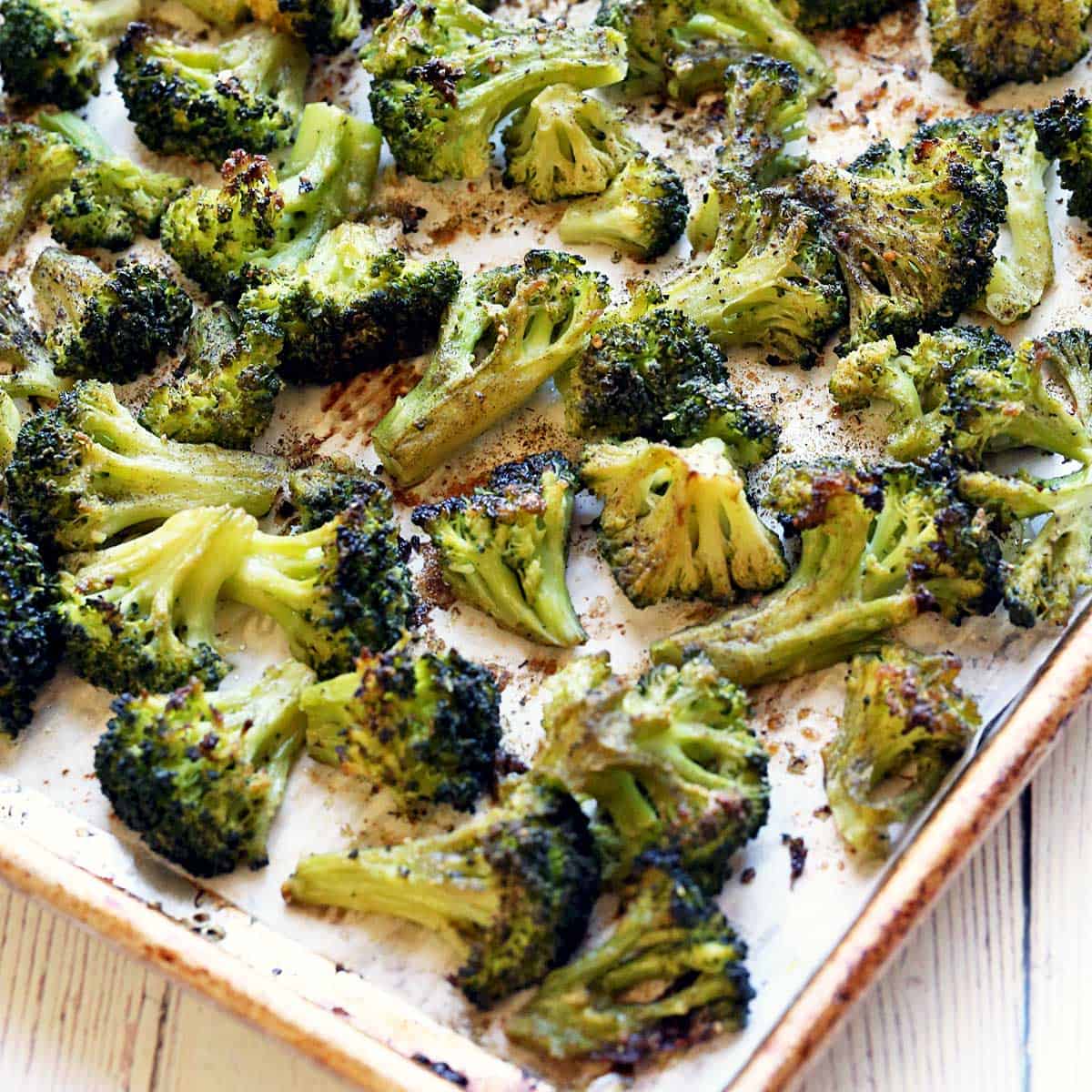Roasted frozen broccoli on a parchment-lined baking sheet.