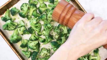 Seasoning the frozen broccoli with black pepper.