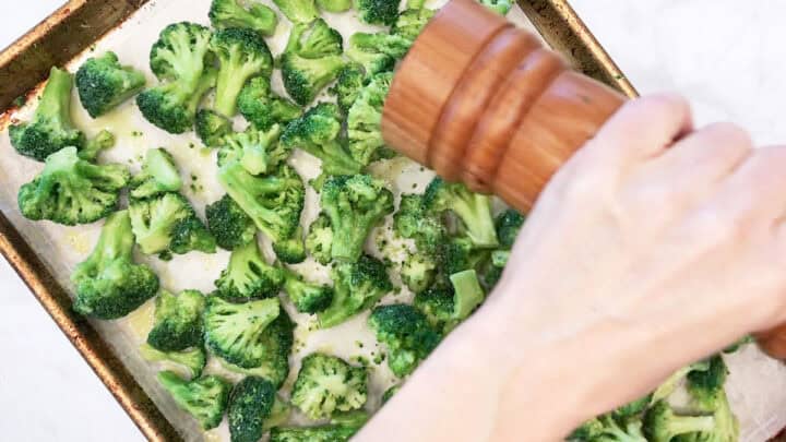 Seasoning the frozen broccoli with black pepper.