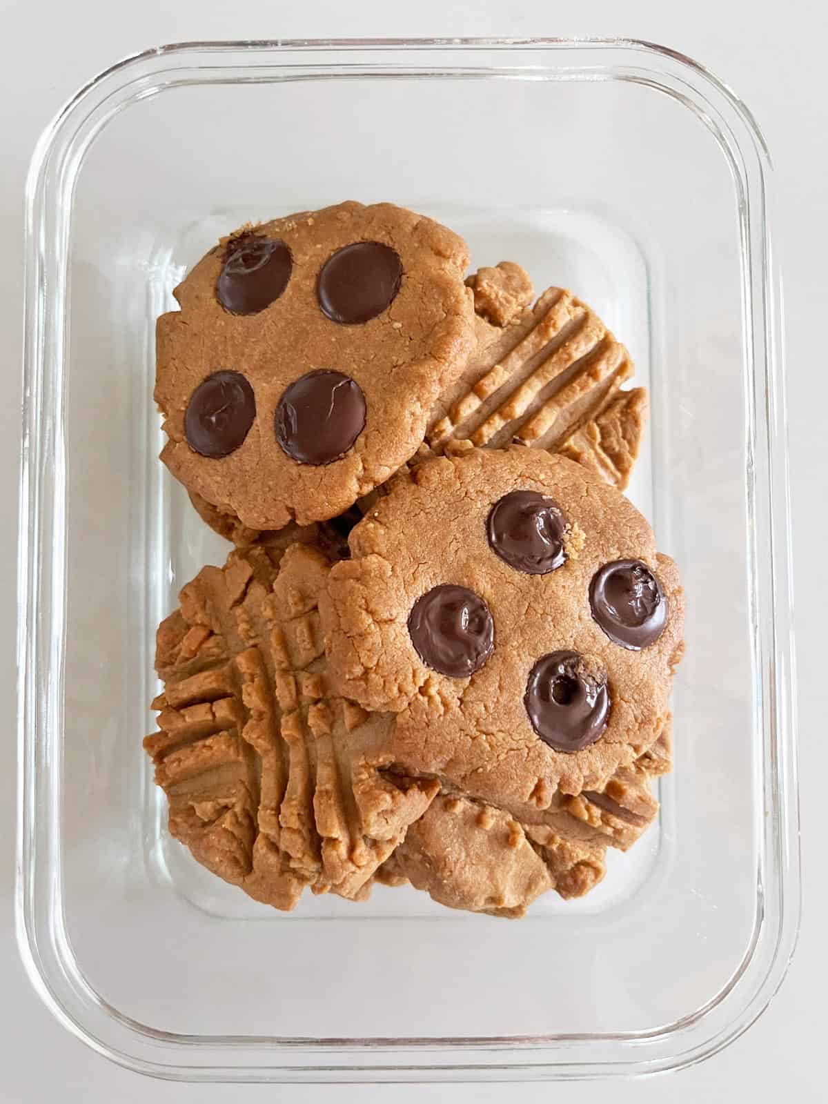 Peanut butter cookies are stored in a glass container.