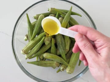 Adding olive oil to the okra.